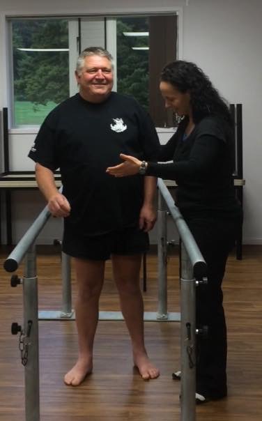 Lisa guiding a client walking between parallel bars