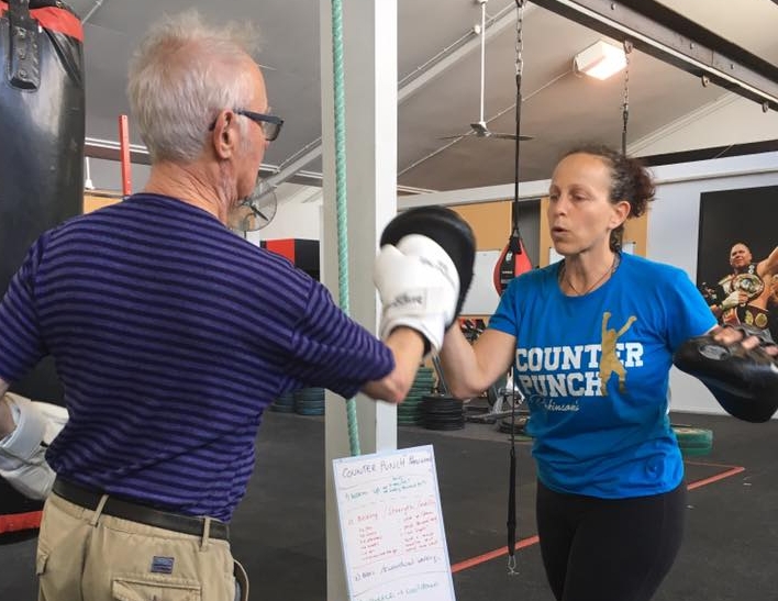 Lisa holding boxing pads for an older client during a Counterpunch Parkinson's session